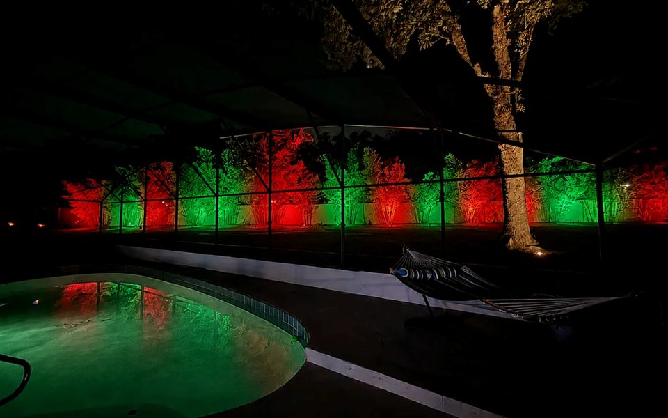 Screened pool area with red and green lights on the landscape